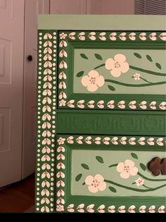 a green dresser with flowers painted on it