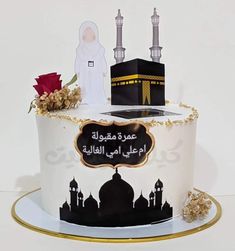 a white cake with black and gold decorations on it's side, topped with an arabic calligraphy