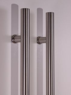 two stainless steel door handles on a white wall