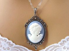 "Blue Cameo Necklace: Renaissance Woman Blue Cameo Necklace, Antiqued Silver, Vintage Inspired Romantic Renaissance Jewelry Romantic Cameo Necklace with beautifully detailed Renaissance woman with flowers and pearls on a slate blue background set in an elegant reproduction antiqued silver plated brass setting. The long rhodium (white gold) plated necklace is designed for the pendant to nestle just above the cleavage, and closes with a lobster clasp. Length: 18 inches Pendant: 3 inches Please lea Blue Cameo Necklace For Wedding, Blue Cameo Jewelry For Wedding, Blue Cameo Necklace For Formal Occasions, Flowers And Pearls, Woman With Flowers, Handsome Prince, Cameo Jewelry, Fantasy Wedding, Cameo Necklace