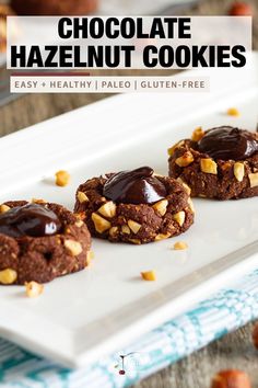 three chocolate hazelnut cookies on a white plate with nuts around the edges and text overlay that reads, chocolate hazelnut cookies