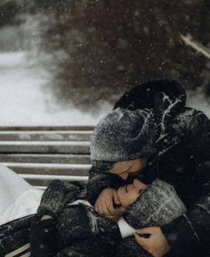 a young boy is sitting on a bench in the snow and holding his head to his chest