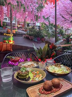 plates of food on a table with pink flowers hanging from the ceiling in front of them