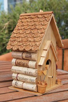 a birdhouse made out of wine corks on top of a wooden table next to a stack of books