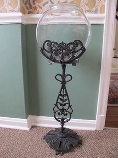 a metal stand with a glass ball on it in front of a green wall and carpeted floor