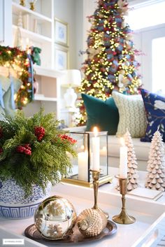 a living room decorated for christmas with candles and ornaments on the coffee table in front of it