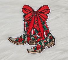 a pair of boots with red bows on them are sitting on a white fur surface