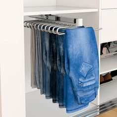 an open closet with several pairs of blue jeans hanging from it's rails and shoes on hangers