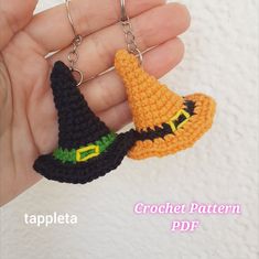 two crocheted witches hats are being held by a hand