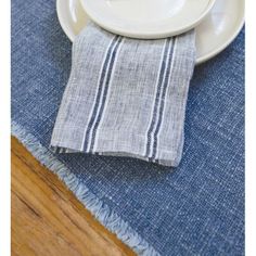 a white plate topped with food next to a blue and white table cloth on top of a wooden table