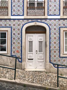 a white door sitting in front of a tall blue and white building with two windows