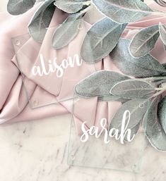 two clear acrylic signs with leaves on them that say, alsian and serah