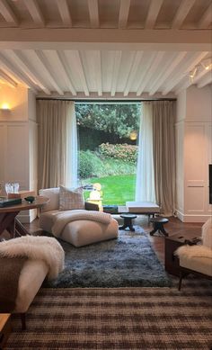 a living room filled with furniture and a large window overlooking a lush green field in the distance