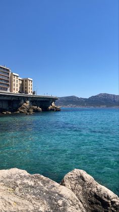 the water is crystal blue and there are buildings in the background on the shore line