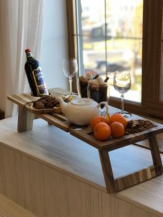 a tray with oranges and other food sitting on a window sill next to a bottle of wine