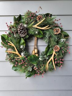 a christmas wreath with antlers, pine cones and holly leaves on a house wall