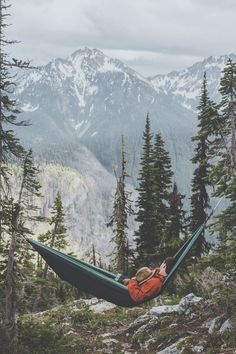 a person laying in a hammock on top of a mountain