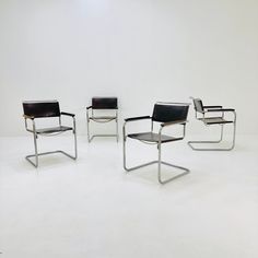 three black leather chairs sitting next to each other on top of a white flooring