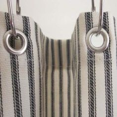 two purses hanging from hooks on a striped curtain with metal rings and ring handles