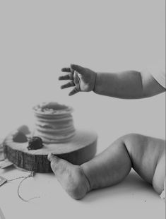 a black and white photo of a baby's hand reaching out towards a cake