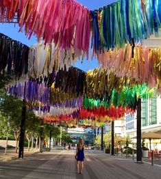 a woman is walking down the street under colorful streamers