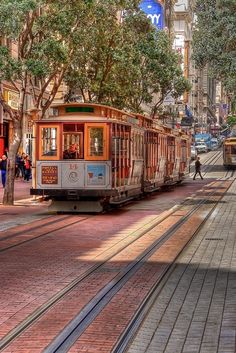 a trolley car traveling down a street next to tall buildings