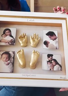 a woman holding up a framed photo with baby's hand and foot prints