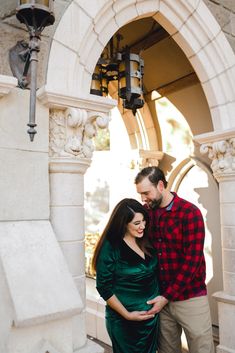 a man and woman standing next to each other in front of a building with an archway