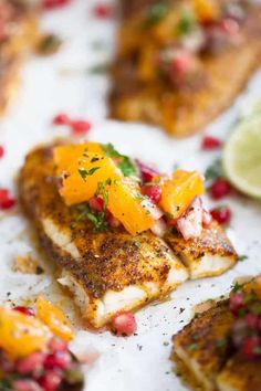 fish with oranges and pomegranate garnishes on top of them