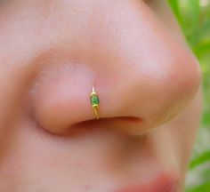 a close up of a person's nose with a tiny green piece on it