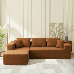 a brown couch sitting on top of a white rug in a living room next to a lamp