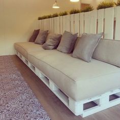 a couch made out of wooden pallets with pillows on it and a rug underneath