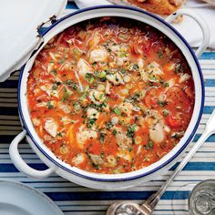 a bowl of vegetable soup with bread on the side and another dish in the background