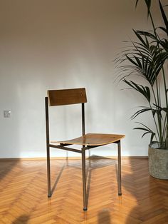 a wooden chair sitting on top of a hard wood floor next to a potted plant