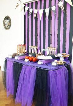 there is a purple and black table with desserts on it, along with other items