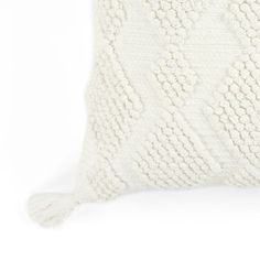 a white knitted pillow with tassels