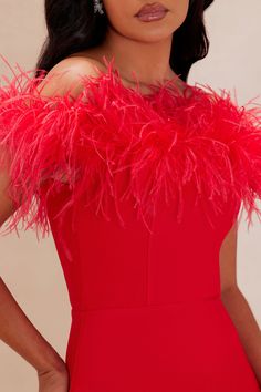 a woman in a red dress with feathers on her shoulders and shoulder, posing for the camera