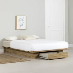 a bed sitting on top of a white floor next to a wooden frame with drawers