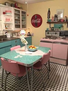 a kitchen with pink chairs and a table in the center, surrounded by blue cabinets