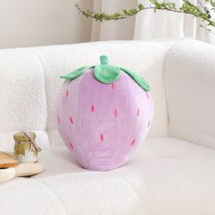 a pink strawberry shaped pillow sitting on top of a white couch