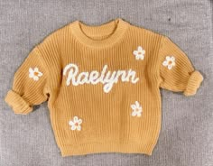 Adorable personalized sweater  Mustard yellow sweater  Ivory letters and daisy flowers If you need any other color, message us Custom orders welcome This is for a hand embroidered sweater  Name and daisy flowers  Up to 10 letter name  Please leave a note with the name you want on the sweater Embroidery Sweaters, Baby Knit Sweater, Hand Embroidered Sweater, Daisy Sweater, Knit Embroidery, Embroidered Sweaters, Mustard Yellow Sweater, Personalized Sweater, Monogram Embroidery