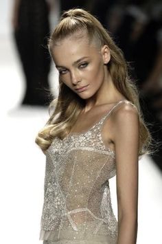 a model walks down the runway in a silver dress