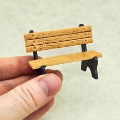 a miniature wooden bench sitting on top of a piece of wood in someone's hand