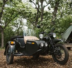 a motorcycle parked next to a tent in the woods