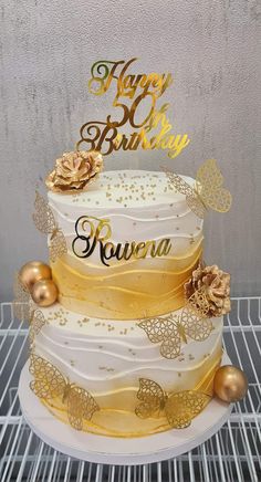 a three tiered cake with gold decorations on top and happy birthday written on the side