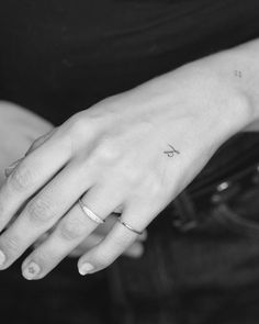 black and white photograph of a woman's hand with a small tattoo on it