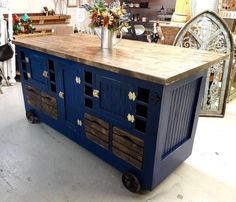 a kitchen island made out of an old blue cabinet with drawers on wheels and wooden top