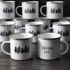 many white coffee mugs with black trees on them sitting on a wooden table next to each other