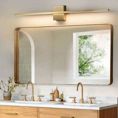 a bathroom vanity with two sinks and a large mirror above it, in front of a window