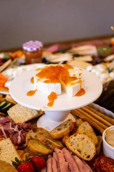 an assortment of cheeses and crackers on a platter with dipping sauce over them